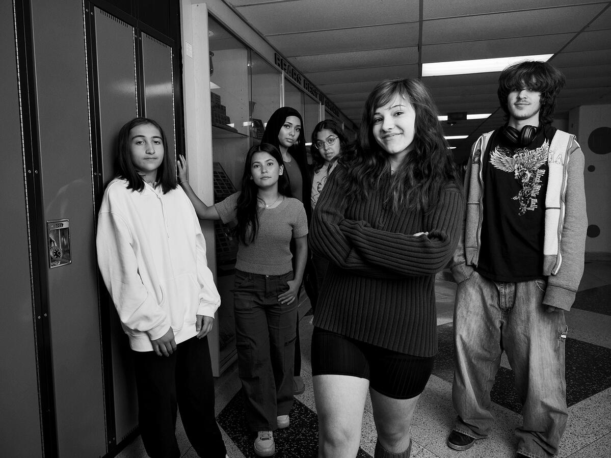 Group of students standing staggered in a hallway of a school. 